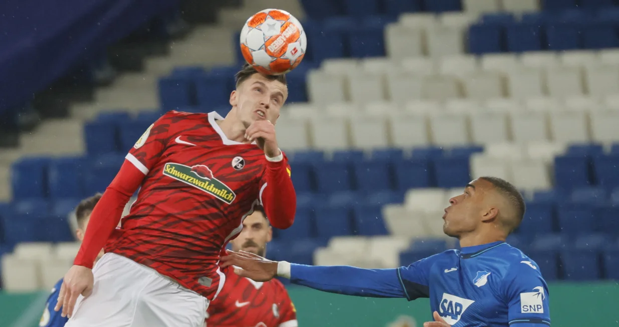 epa09695696 Freiburg's Ermedin Demirovic (L) in action against Hoffenheim's Kevin Akpoguma (R) during the German DFB Cup round of 16 soccer match between TSG Hoffenheim and SC Freiburg in Sinsheim, Germany, 19 January 2022. EPA/RONALD WITTEK CONDITIONS - ATTENTION: The DFB regulations prohibit any use of photographs as image sequences and/or quasi-video.