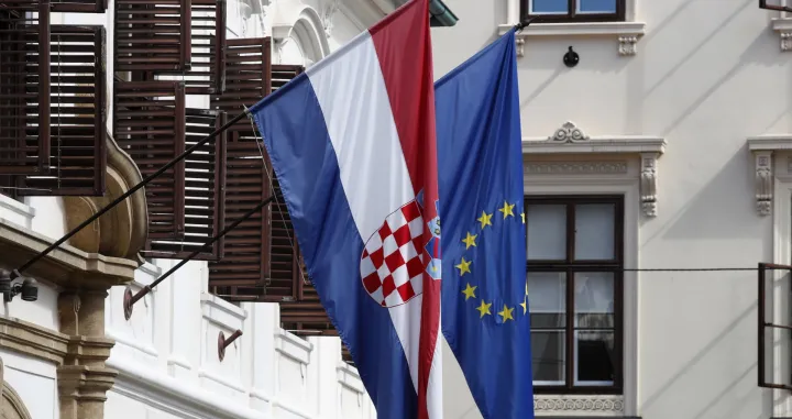 epa10066356 Croatian and European Union flags in Zagreb, Croatia, 12 July 2022. EU Finance Ministers on 12 July will set the exchange rate at which the Croatian Kuna currency (HRK) will be converted into euro when Croatia adopts the single currency on 01 January 2023. EPA/ANTONIO BAT/Antonio Bat