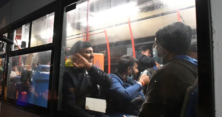 epa10294896 Rescued migrants gesture from a bus after disembarking from the Geo Barents ship as it is docked on the quay of 'pier ten' of the port of Catania, Sicily island, southern Italy, 08 November 2022. EPA/ORIETTA SCARDINO Foto: Orietta Scardino