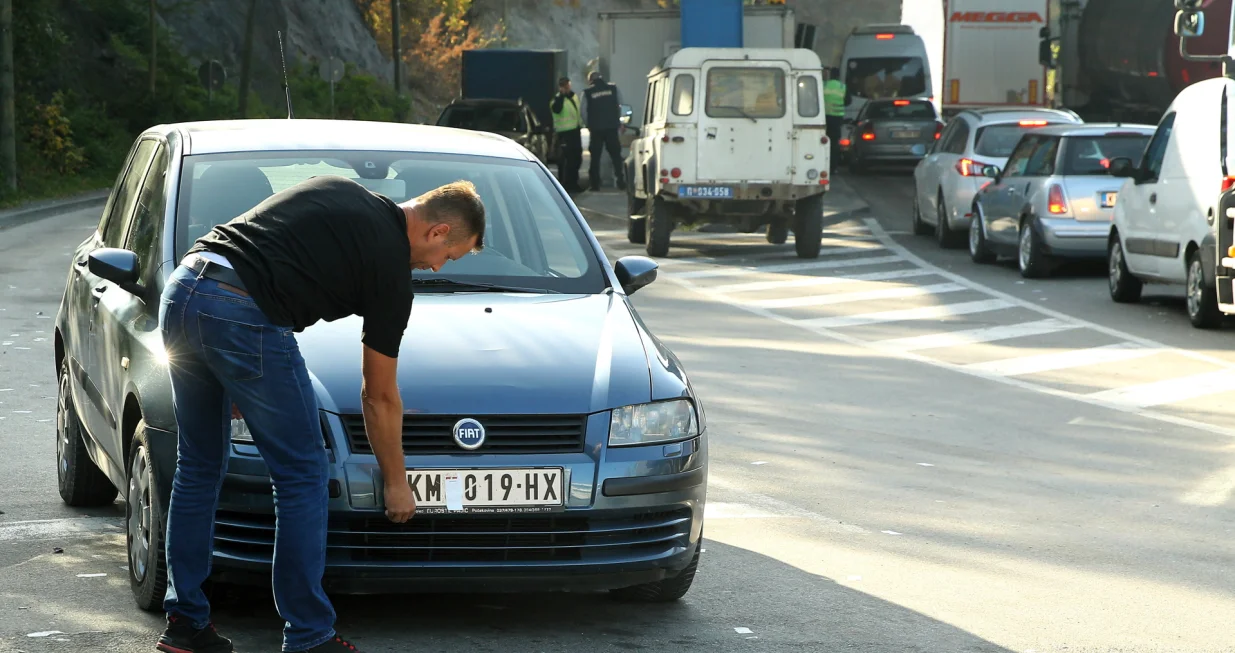 epa10279186 A motorist takes off stickers covering the national markings on his car license plates at the Jarinje border crossing between Kosovo and Serbia at Jarinje, Serbia, 01 November 2022. The Government of Kosovo will begin implementing a plan to eliminate the usage of Serbian car license plates. All owners of vehicles with Serbian number plates are warned and requested to visit any of the Vehicle Registration Centers and register their vehicles with RKS license plates. In the Serbian community of Kosovo, the RKS license plates are seen as unacceptable as they suggest the recognition of independence of the Republic of Kosovo. EPA/DJORDJE SAVIC/Djordje Savic