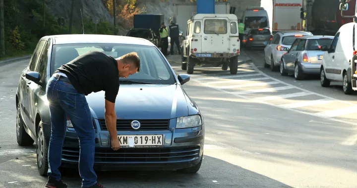 epa10279186 A motorist takes off stickers covering the national markings on his car license plates at the Jarinje border crossing between Kosovo and Serbia at Jarinje, Serbia, 01 November 2022. The Government of Kosovo will begin implementing a plan to eliminate the usage of Serbian car license plates. All owners of vehicles with Serbian number plates are warned and requested to visit any of the Vehicle Registration Centers and register their vehicles with RKS license plates. In the Serbian community of Kosovo, the RKS license plates are seen as unacceptable as they suggest the recognition of independence of the Republic of Kosovo. EPA/DJORDJE SAVIC/Djordje Savic