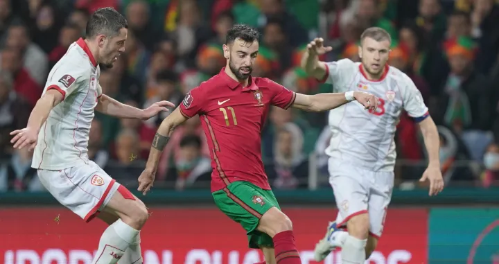 epa09859255 Portugal player Bruno Fernandes (C) in action against North Macedonia player Stefan Ristovski during the FIFA World Cup Qatar 2022 play-off qualifying soccer match Portugal vs North Macedonia held on Dragao stadium in Porto, Portugal, 29 March 2022. EPA/HUGO DELGADO