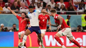 epa10337231 Jude Bellingham (C) of England in action against Joe Allen (L) of Wales during the FIFA World Cup 2022 group B soccer match between Wales and England at Ahmad bin Ali Stadium in Doha, Qatar, 29 November 2022. EPA/Friedemann Vogel