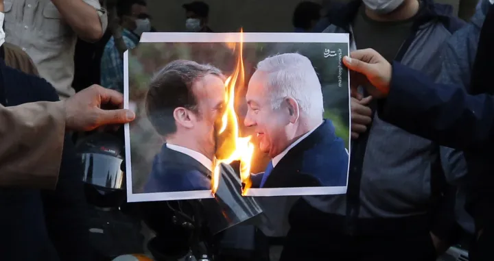 epa08780732 Iranians burn a picture depicting French President Emanuel Macron and Israel President Benjamin Netanyahu, during an anti-France protest demonstration in front of the French embassy in Tehran, Iran, 28 October 2020. Media reported that President Rouhani has condemned insulting to Prophet Muhammad and asked those who caused (referring to French President Emanuel Macron) this to apologize to Islam world. Macron's comments came after the recent beheading of a teacher in France after he had shown cartoons of the Prophet Muhammad in class. French President Macron vowed his country would not give up publishing such cartoons. EPA/ABEDIN TAHERKENAREH/Abedin Taherkenareh