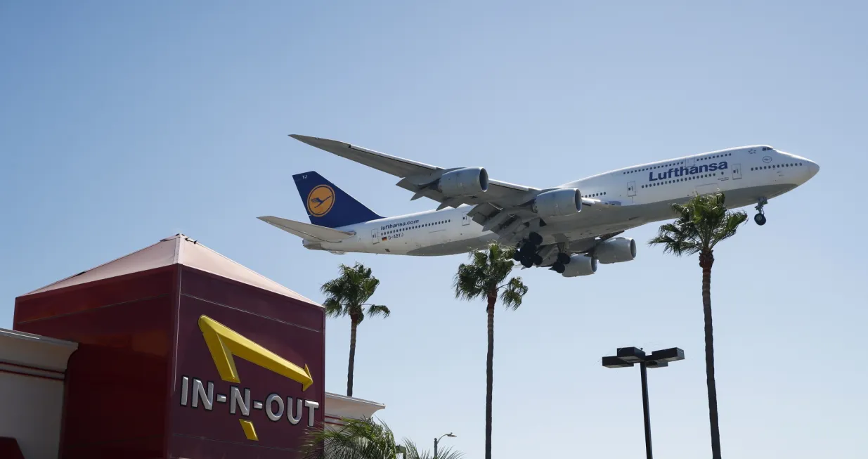 epa10210734 A Lufthansa Boeing 747-830 with tail number D-ABYJ flies over an In-N-Out Burger as it approaches the Los Angeles International Airport, in Los Angeles, California, USA, 27 September 2022. US President Joe Biden announced on 26 September plans to require airlines and travel sites to be more transparent about additional fees for customers, calling them 'unnecessary hidden fees'. EPA/CAROLINE BREHMAN/Caroline Brehman