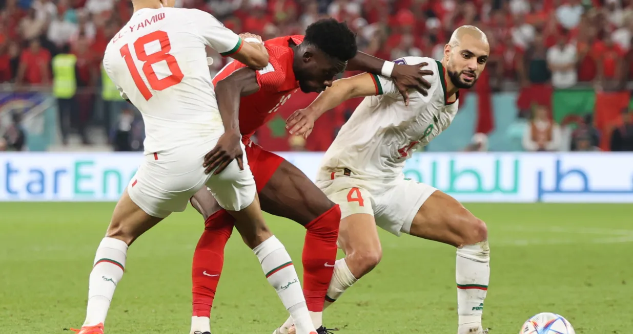 epa10342030 Alphonso Davies (C) of Canada in action against Sofyan Amrabat (R) of Morocco during the FIFA World Cup 2022 group F soccer match between Canada and Morocco at Al Thumama Stadium in Doha, Qatar, 01 December 2022. EPA/Mohamed Messara