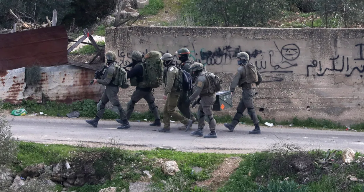 epa10386225 Israeli soldiers take positions during operation to demolish homes belonging to Palestinians accused of killing an Israeli soldier, in the West Bank village of Kafr Dan, near Jenin city, 02 January 2023. The Israeli army said Israeli forces came under attack as they entered the Kafr Dan village to demolish houses of two Palestinians accused of shooting and killing Major Bar Falah in September 2022. The Palestinian Ministry of Health said two Palestinians were killed during the Israeli raid identified as 22-year-old Muhammad Houshiyeh and 25-year-old Fouad Abed. EPA/ALAA BADARNEH 4605/Alaa Badarneh