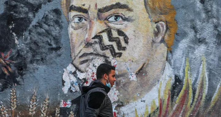 epa08813894 A Palestinian man walks past an anti- USA President Donald Trump mural in the street of Gaza City, 11 November 2020. EPA/MOHAMMED SABER/Mohammed Saber