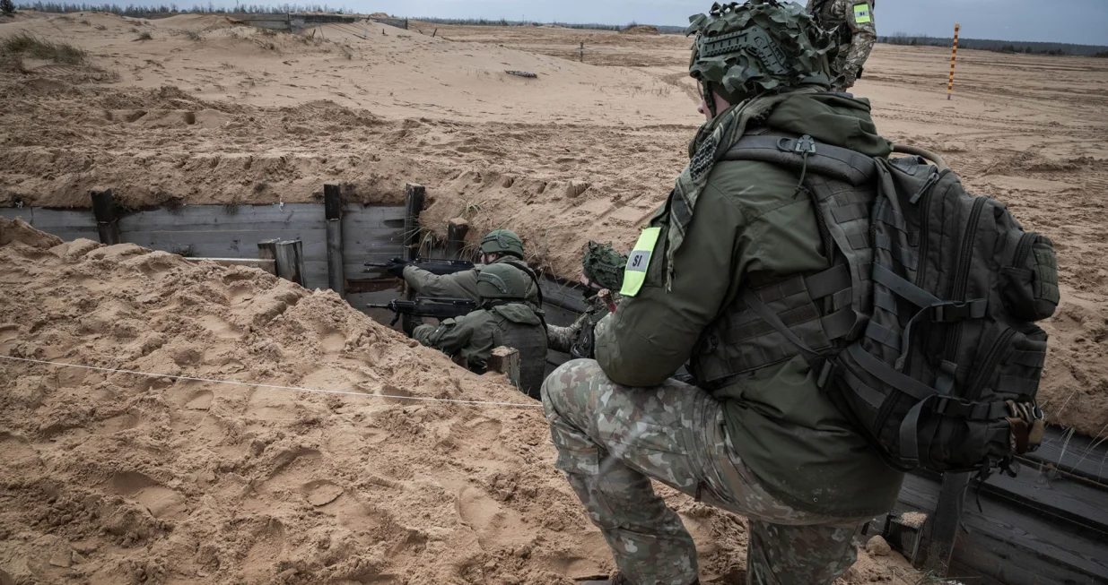 A Lithuanian instructor assists two Ukrainian soldiers standing in a trench during an eight-week training course./Nato