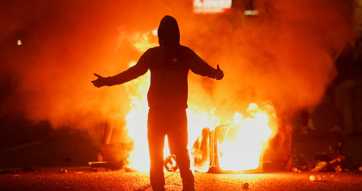 Fire burns near a demonstrator as riots continue in Ballymena, Northern Ireland, June 11, 2025. REUTERS/Clodagh Kilcoyne TPX IMAGES OF THE DAY/Clodagh Kilcoyne
