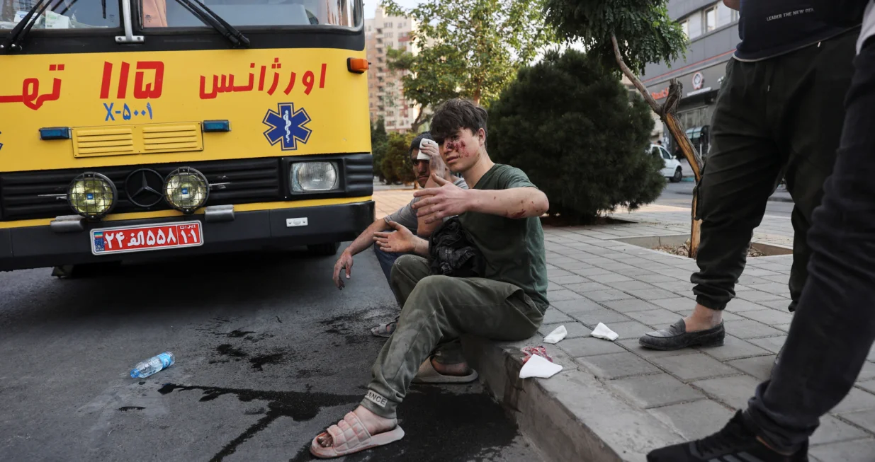An injured person sits on a roadside in the aftermath of Israeli strikes, in Tehran, Iran, June 13, 2025. Majid Asgaripour/WANA (West Asia News Agency) via REUTERS ATTENTION EDITORS - THIS PICTURE WAS PROVIDED BY A THIRD PARTY TPX IMAGES OF THE DAY/Majid Asgaripour