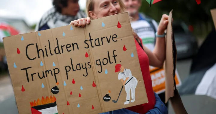 A woman holds a placard as demonstrators protest the visit of U.S. President Donald Trump, in Balmedie, near Aberdeen, Scotland, Britain, July 28, 2025. REUTERS/Hannah McKay/Hannah Mckay