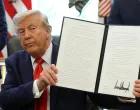 U.S. President Donald Trump holds up an executive order after signing it in the Oval Office at the White House in Washington, D.C., U.S., August 25, 2025. REUTERS/Jonathan Ernst  TPX IMAGES OF THE DAY/Jonathan Ernst