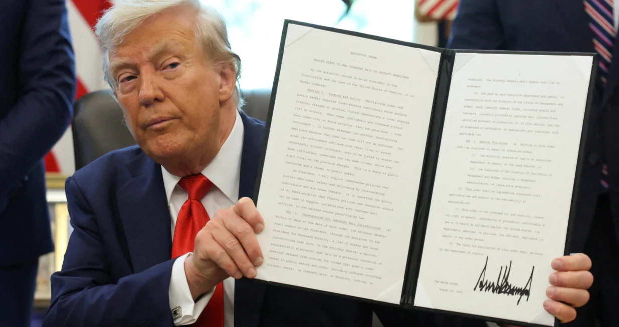 U.S. President Donald Trump holds up an executive order after signing it in the Oval Office at the White House in Washington, D.C., U.S., August 25, 2025. REUTERS/Jonathan Ernst TPX IMAGES OF THE DAY/Jonathan Ernst