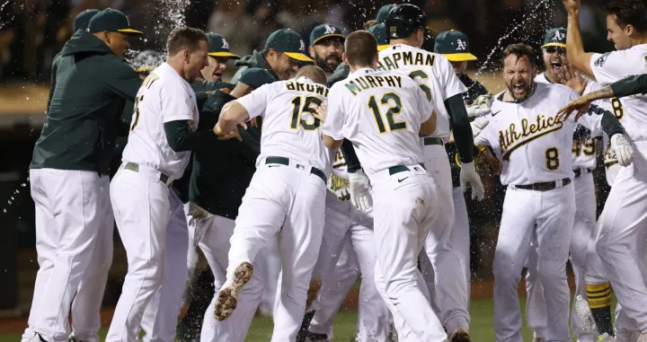 epa09349757 Oakland Athletics Jed Lowrie (2-R) is mobbed by his teammates after hitting a game winning walk-off two run home run off Cleveland Indians relief pitcher Emmanuel Clase during the ninth inning of the Major League Baseball (MLB) game between the Cleveland Indians and the Oakland Athletics at RingCentral Coliseum in Oakland, California, USA, 16 July 2021. EPA/JOHN G. MABANGLO/Foto: John G. Mabanglo