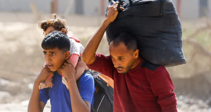Palestinians, who were displaced to the southern part of Gaza at Israel's order during the war, carry their belongings and a child, while they return to the north, amid a ceasefire between Israel and Hamas in Gaza, in the central Gaza Strip, October 12, 2025. REUTERS/Mahmoud Issa/Mahmoud Issa
