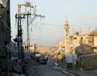People walk past damaged electricity poles in Nuseirat, central Gaza Strip, October 31, 2025. REUTERS/Mahmoud Issa/Mahmoud Issa