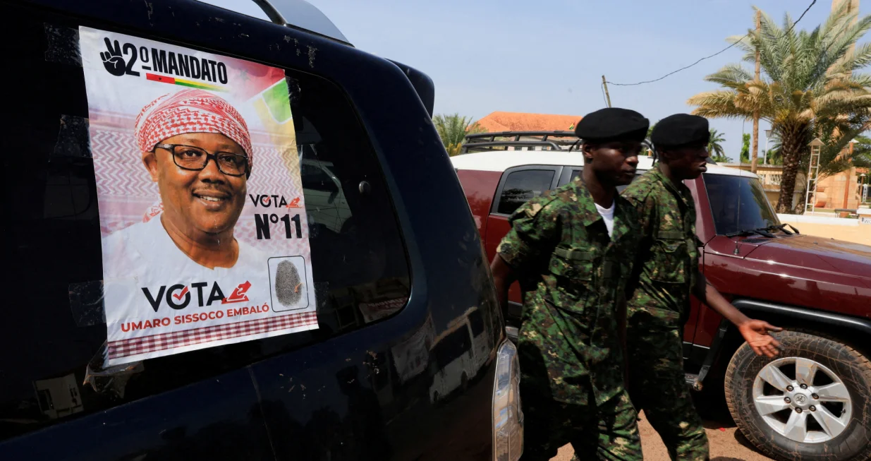 FILE PHOTO: Soldiers walk near a campaign poster of Guinea-Bissau's incumbent President Umaro Sissoco Embalo, ahead of the presidential election scheduled for November 23, in Bissau, Guinea-Bissau November 20, 2025. REUTERS/Luc Gnago/File Photo/Luc Gnago