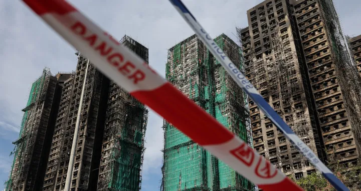 Police cordons are placed at the scene of the Wang Fuk Court housing estate fire as mourners pay tribute to the victims, in Tai Po, Hong Kong, China, November 28, 2025. REUTERS/Tyrone Siu/Tyrone Siu