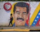 A woman walks past a mural of Venezuela's President Nicolas Maduro amid rising tensions between the administration of U.S. President Donald Trump and the government of Venezuela's President Nicolas Maduro, in Caracas, Venezuela, November 24, 2025. REUTERS/Gaby Oraa/Gaby Oraa