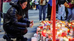 A woman places a candle outside the "Le Constellation" bar, after a fire and explosion during a New Year's Eve party where people died, and others were injured, in the upscale ski resort of Crans-Montana in southwestern Switzerland, January 2, 2026. REUTERS/Stephanie Lecocq  TPX IMAGES OF THE DAY/Stephanie Lecocq