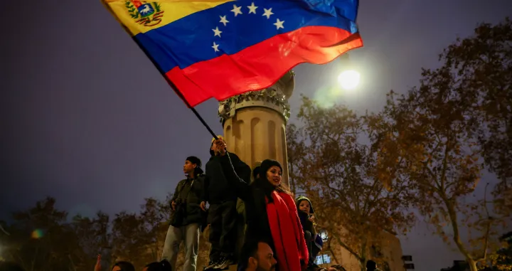 A woman waves a large Venezuelan flag as Venezuelans and others celebrate in Barcelona following Saturday's U.S. strikes on Venezuela, during which President Nicolas Maduro and his wife, Cilia Flores, were captured, Spain, January 4, 2026. REUTERS/Bruna Casas  TPX IMAGES OF THE DAY/Bruna Casas