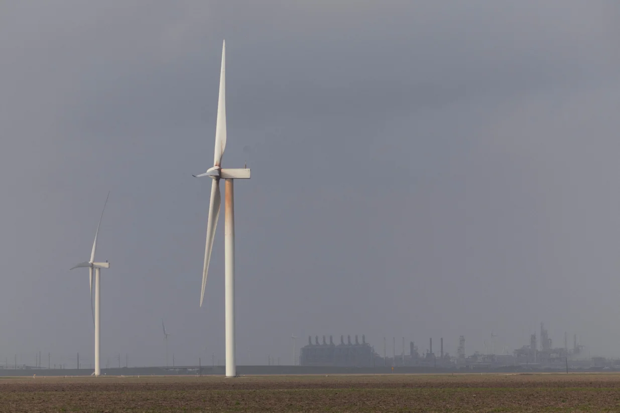 Wind turbine blades spin with the Gulf Coast Growth Ventures (GCGV) Petrochemical Complex in the background, in Gregory, Texas, U.S., January 8, 2026. REUTERS/Antranik Tavitian/Foto: Antranik Tavitian
