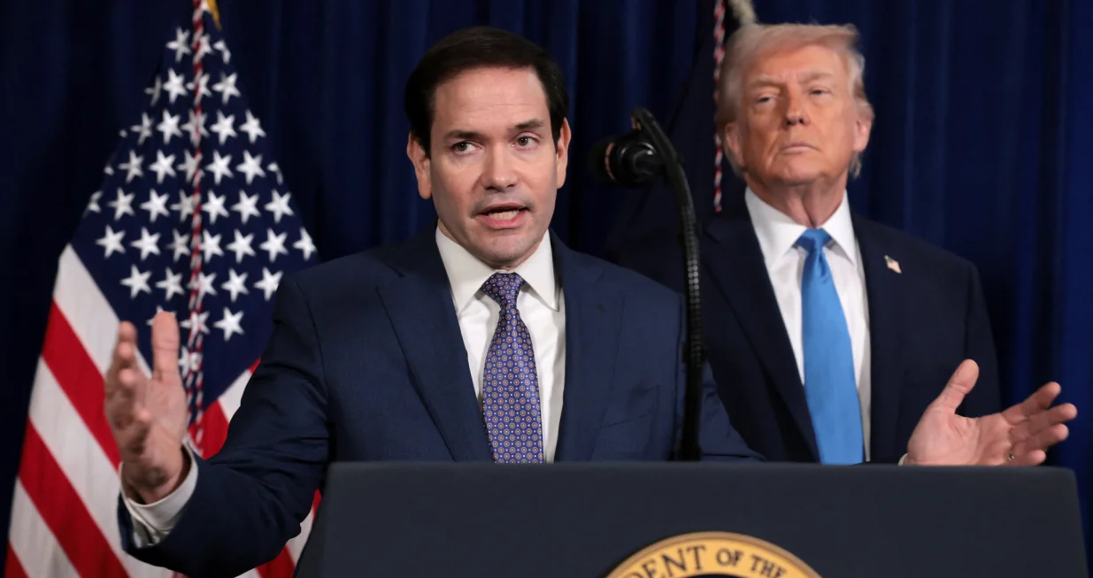 U.S. Secretary of State Marco Rubio speaks as U.S. President Donald Trump stands behind him during a press conference following a U.S. strike on Venezuela where President Nicolas Maduro and his wife, Cilia Flores, were captured, from Trump's Mar-a-Lago club in Palm Beach, Florida, U.S., January 3, 2026. REUTERS/Jonathan Ernst/Jonathan Ernst