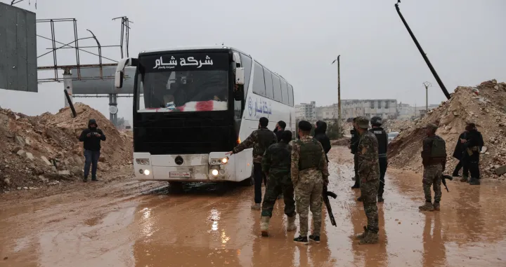A bus driver speaks with members of the Syrian army, after an agreement failed between Syrian Democratic Forces (SDF) with the Syrian government, where SDF members were supposed to evacuate to northeastern Syria after days of fighting with the Syrian army, in Aleppo, Syria, January 9, 2026. REUTERS/Khalil Ashawi/Khalil Ashawi