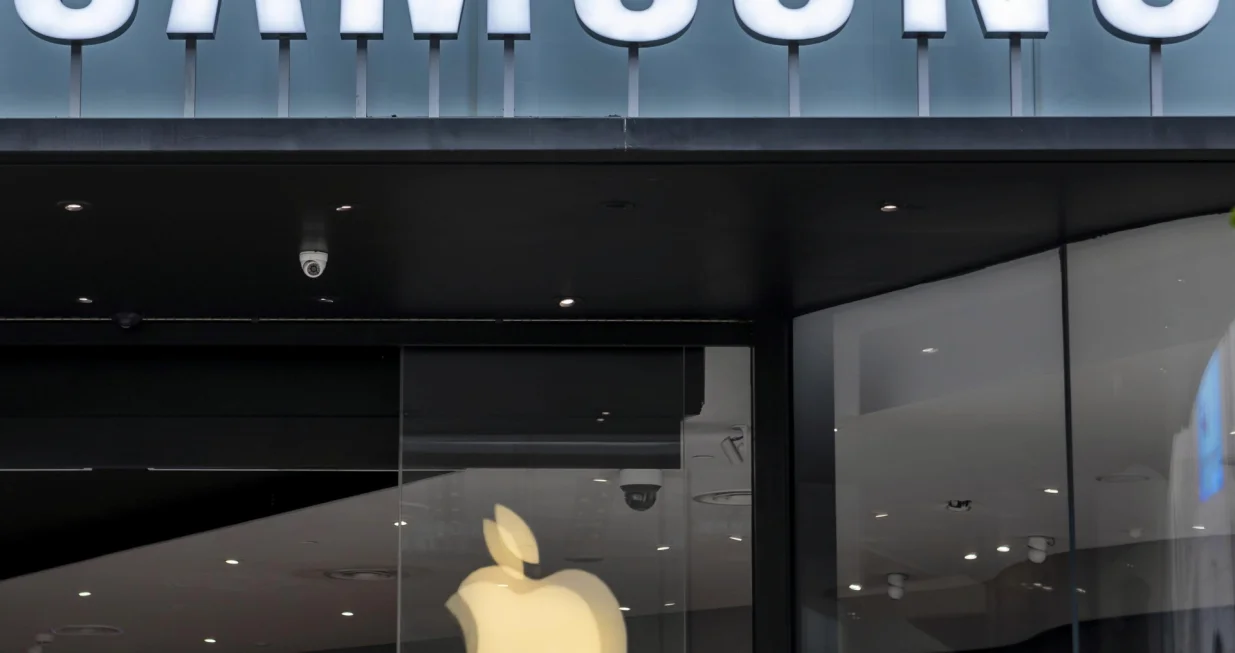 epa08544846 Apple logo is seen reflected on a Samsung store window in Shanghai, China, 14 July 2020. The World Health Organization (WHO) has confirmed the deployment of an epidemiologist and an animal diseases specialist in an effort to trace the origin of the virus. EPA/ALEX PLAVEVSKI/Alex Plavevski