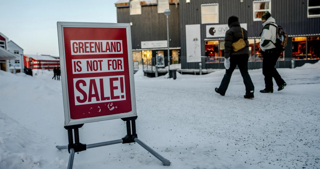 People walk past a sign placed on a street in Nuuk, Greenland, Tuesday, January 20, 2026. Ritzau Scanpix/ Mads Claus Rasmussen via REUTERS ATTENTION EDITORS - THIS IMAGE WAS PROVIDED BY A THIRD PARTY. DENMARK OUT. NO COMMERCIAL OR EDITORIAL SALES IN DENMARK./Mads Claus Rasmussen