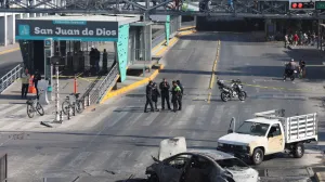 Police officers and civilians walk near the burned wreckage of a vehicle used as a barricade by members of organized crime following a series of detentions by federal forces, in Guadalajara, Mexico, February 22, 2026. REUTERS/Michelle Freyria REFILE - UPDATING SLUG/Michelle Freyria
