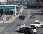 Police officers and civilians walk near the burned wreckage of a vehicle used as a barricade by members of organized crime following a series of detentions by federal forces, in Guadalajara, Mexico, February 22, 2026. REUTERS/Michelle Freyria REFILE - UPDATING SLUG/Michelle Freyria