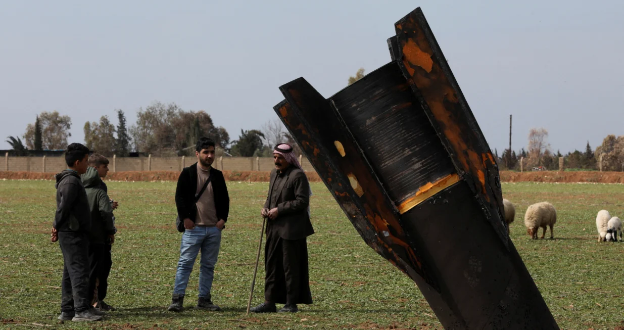 People stand next to a missile after it fell near Qamishli International Airport, amid the U.S.-Israeli conflict with Iran, in Qamishli, Syria, March 4, 2026. REUTERS/Orhan Qereman REFILE &ndash; REMOVING ATTRIBUTION OF THE MISSILE/Orhan Qereman