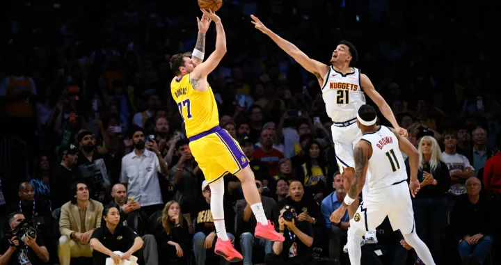 Mar 14, 2026; Los Angeles, California, USA; Los Angeles Lakers guard Luka Doncic (77) shoots a game winning shot while under pressure from Denver Nuggets forward Spencer Jones (21) during overtime at Crypto.com Arena. Mandatory Credit: William Liang-Imagn Images/Foto: William Liang